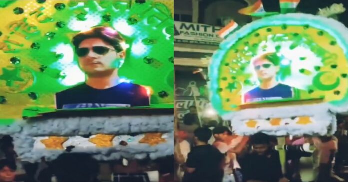 मुहर्रम जुलूस में भरत तिवारी की तस्वीर वाला सिफल देखते लोग।