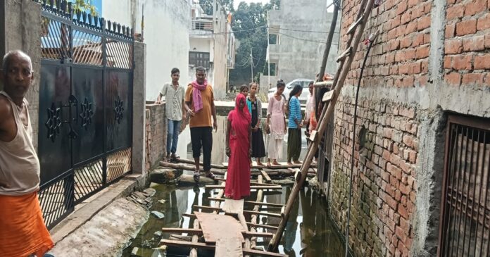 नीलकंठ नगर कॉलोनी में जलभराव के बीच बनाया गया लकड़ी का पुल