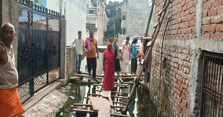 नीलकंठ नगर कॉलोनी में जलभराव के बीच बनाया गया लकड़ी का पुल